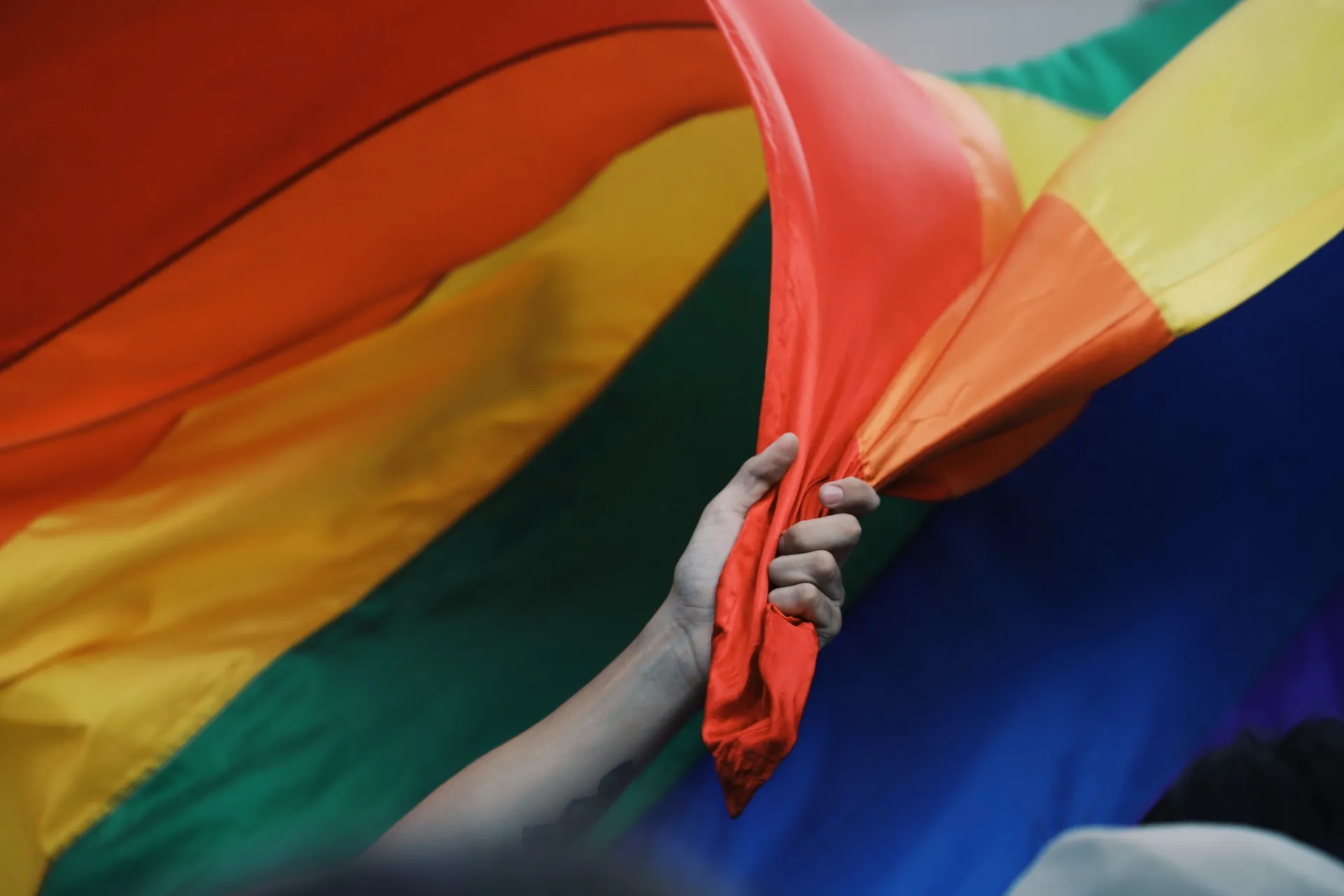 a hand holding a Gay Pride flag