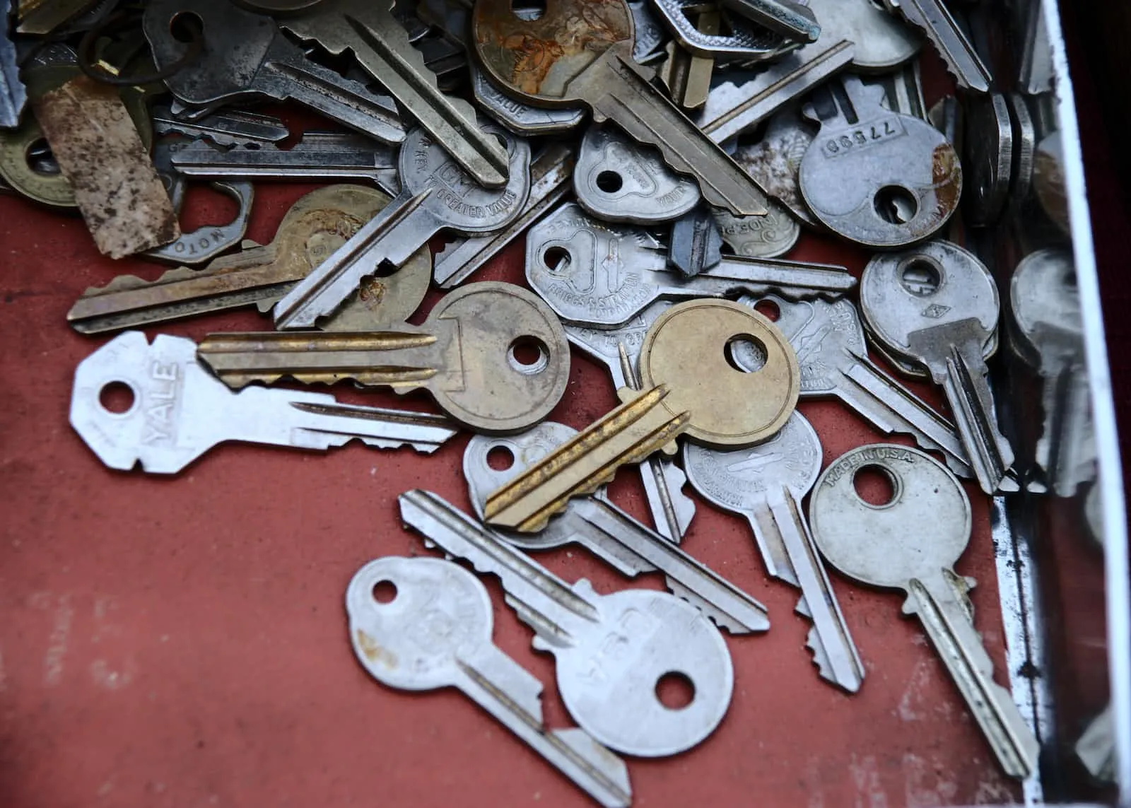 Many door keys scattered on a red surface